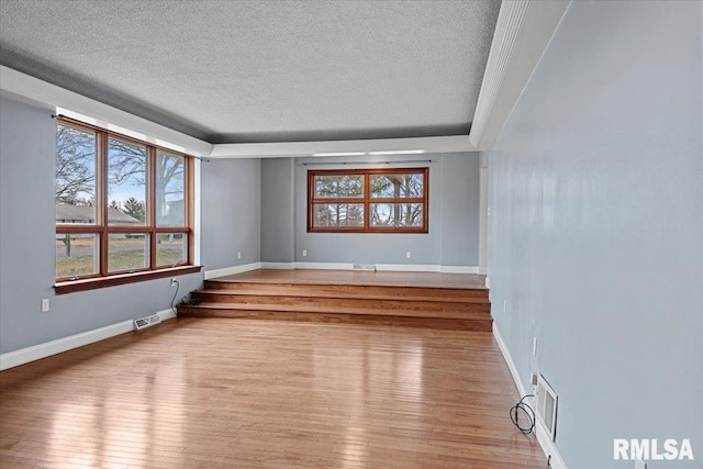 unfurnished room with a textured ceiling and light hardwood / wood-style floors