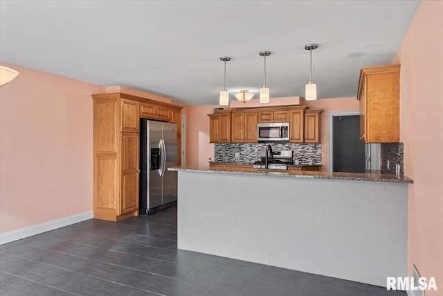 kitchen featuring tasteful backsplash, kitchen peninsula, dark stone countertops, and stainless steel appliances