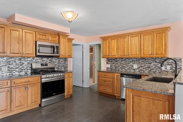 kitchen featuring decorative backsplash, dark stone countertops, sink, and appliances with stainless steel finishes