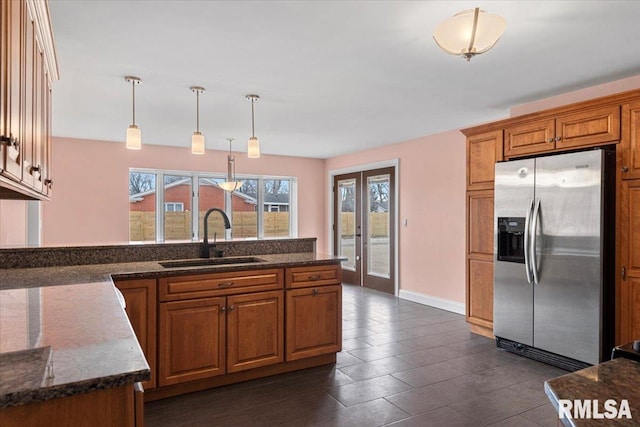 kitchen with sink, french doors, stainless steel refrigerator with ice dispenser, dark stone counters, and decorative light fixtures