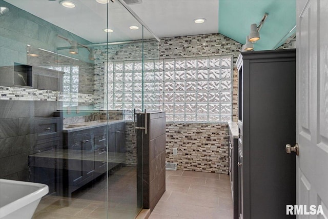 bathroom featuring plus walk in shower, vaulted ceiling, tile patterned floors, and tile walls