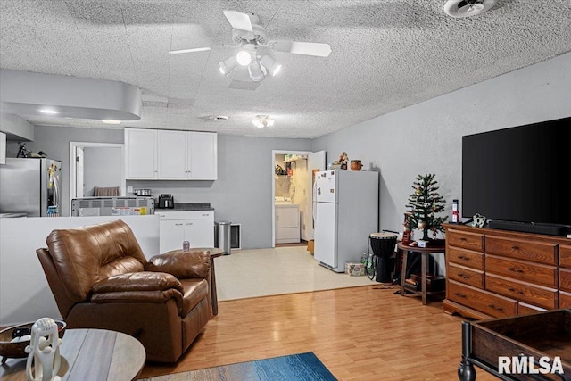 living room with washer / clothes dryer, light hardwood / wood-style flooring, and ceiling fan