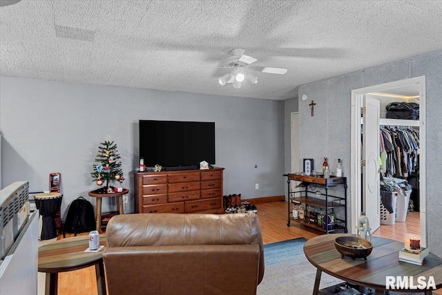 living room with wood-type flooring, a textured ceiling, and ceiling fan