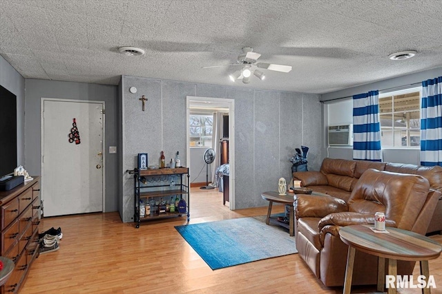 living room featuring ceiling fan, cooling unit, a wealth of natural light, and light hardwood / wood-style flooring