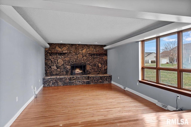 unfurnished living room with a fireplace, light hardwood / wood-style floors, and a textured ceiling