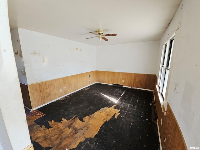 unfurnished room with ceiling fan and wooden walls