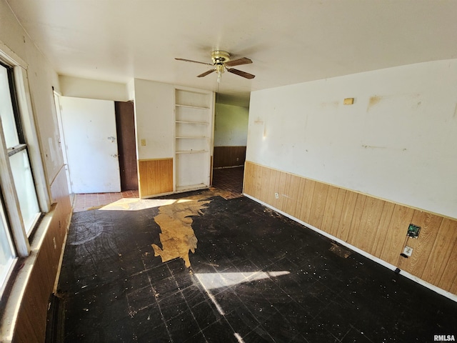 spare room with ceiling fan and wooden walls