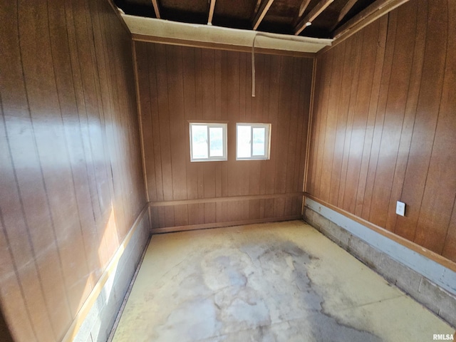 empty room featuring wooden walls and concrete floors