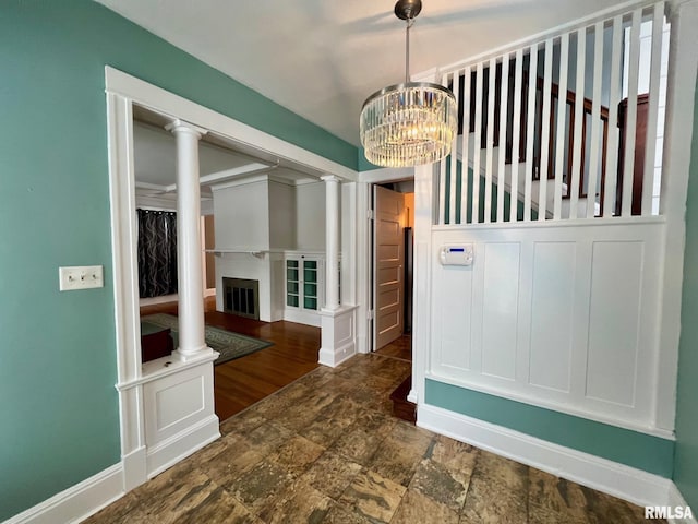 unfurnished dining area with decorative columns and a notable chandelier