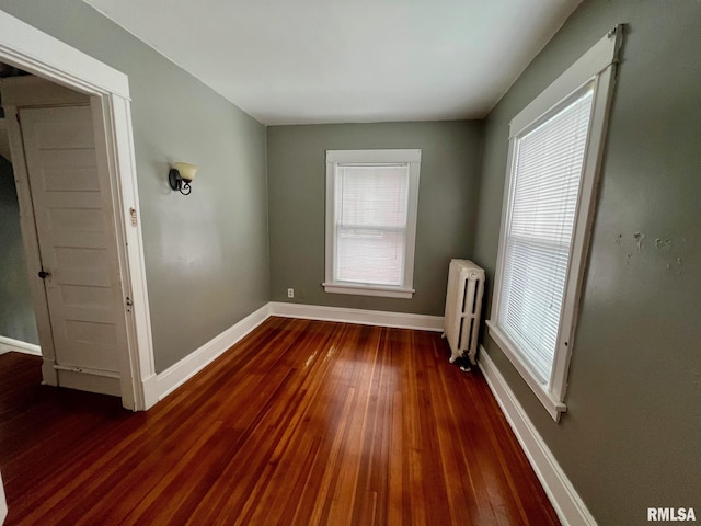 unfurnished room with radiator, a wealth of natural light, and dark hardwood / wood-style floors