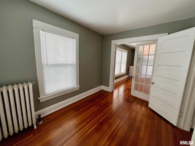 empty room with dark hardwood / wood-style flooring and radiator heating unit