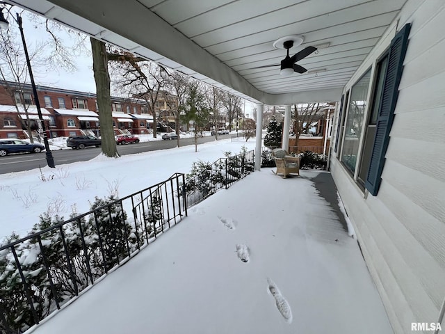 yard covered in snow with ceiling fan and a porch