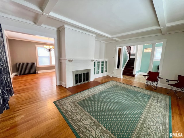 living room with radiator, coffered ceiling, hardwood / wood-style flooring, a notable chandelier, and beamed ceiling