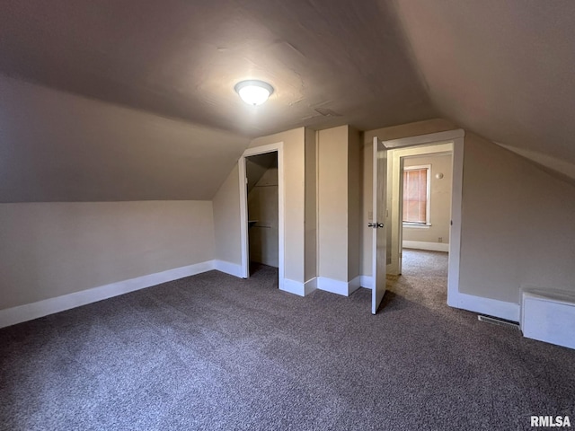 bonus room featuring dark carpet and vaulted ceiling