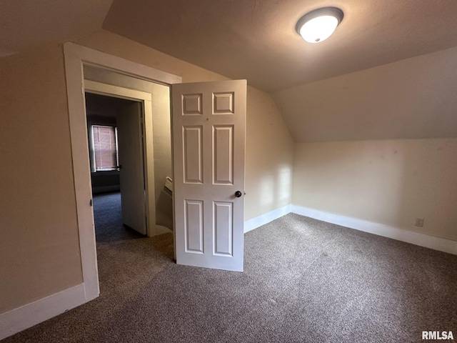 bonus room with dark carpet and vaulted ceiling