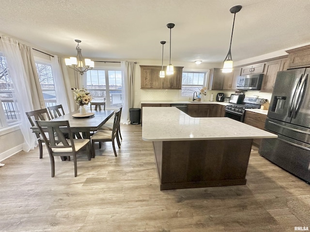 kitchen featuring a kitchen island, pendant lighting, a notable chandelier, and appliances with stainless steel finishes