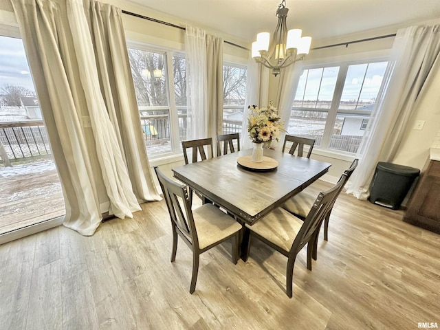 dining space with light hardwood / wood-style floors and a notable chandelier