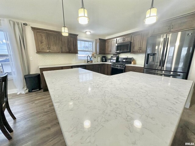 kitchen with backsplash, pendant lighting, stainless steel appliances, and sink