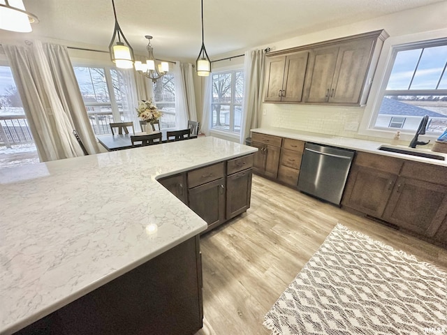 kitchen with tasteful backsplash, stainless steel dishwasher, sink, decorative light fixtures, and a notable chandelier