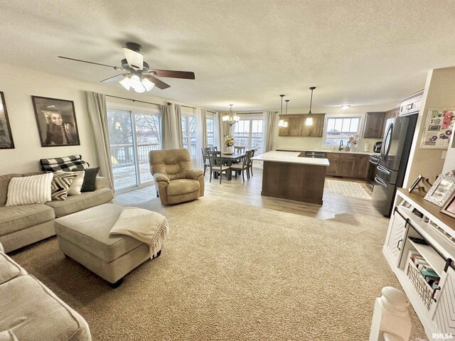 living room featuring ceiling fan with notable chandelier, sink, and a textured ceiling