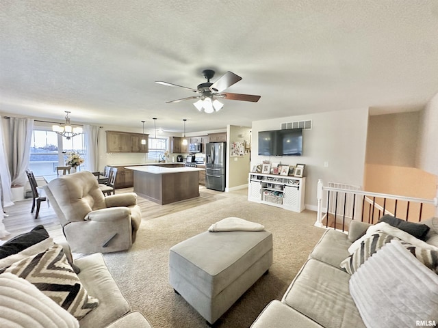 living room with ceiling fan with notable chandelier and a textured ceiling