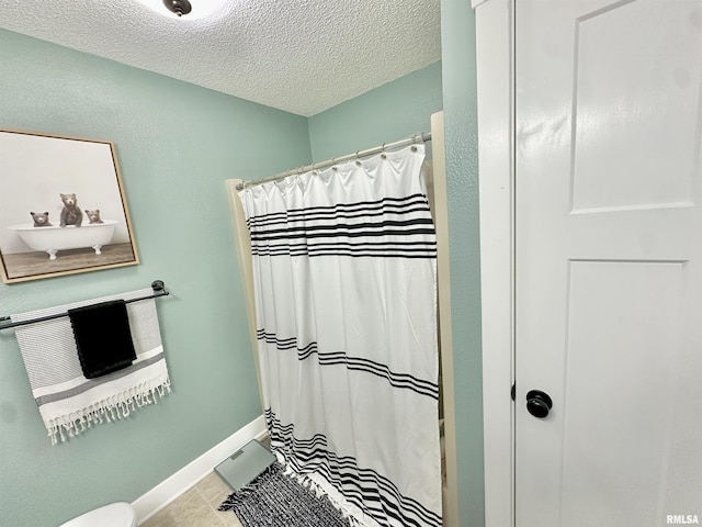 bathroom with tile patterned flooring, a textured ceiling, and walk in shower