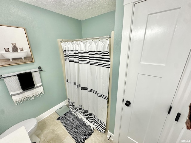 bathroom with tile patterned floors, curtained shower, toilet, and a textured ceiling