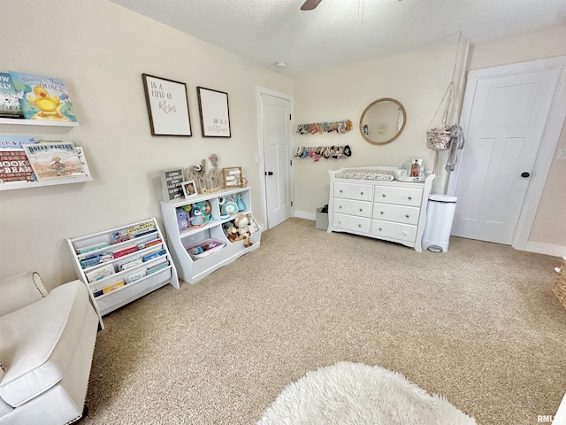 recreation room with carpet, ceiling fan, and a textured ceiling