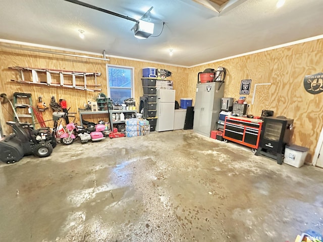 garage with white fridge, a garage door opener, and wood walls