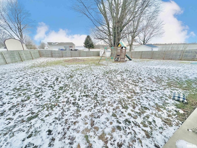 snowy yard featuring a playground