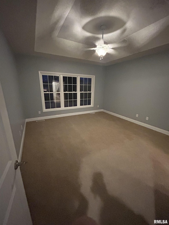 unfurnished room featuring ceiling fan, a tray ceiling, and carpet flooring