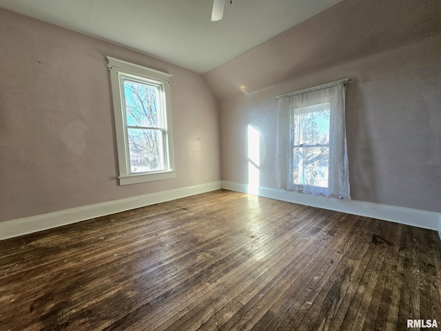 additional living space with ceiling fan, plenty of natural light, dark wood-type flooring, and vaulted ceiling