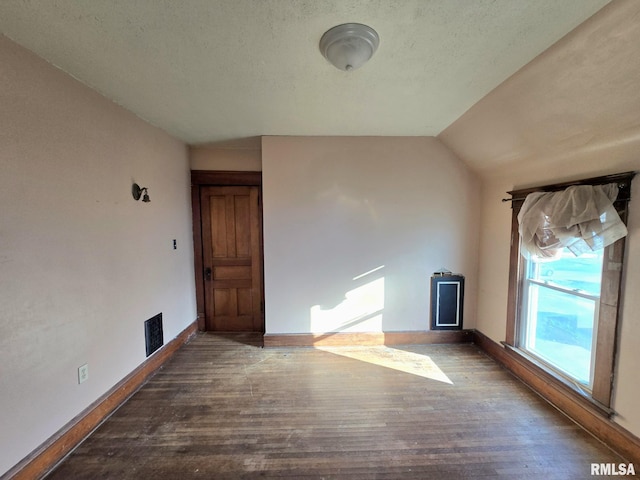 unfurnished living room featuring a textured ceiling, dark wood-type flooring, and vaulted ceiling