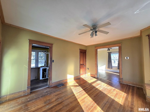 unfurnished room featuring ceiling fan with notable chandelier, dark hardwood / wood-style floors, and crown molding