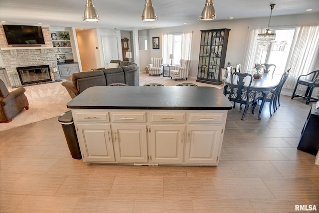 kitchen with white cabinets, decorative light fixtures, a center island, and a fireplace