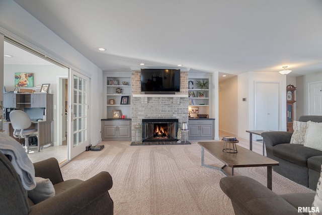 living room with built in shelves, light colored carpet, a fireplace, and french doors