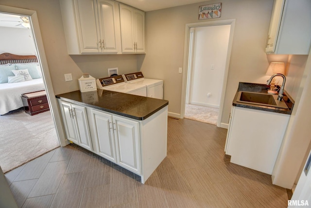 kitchen featuring washing machine and clothes dryer, sink, and white cabinets