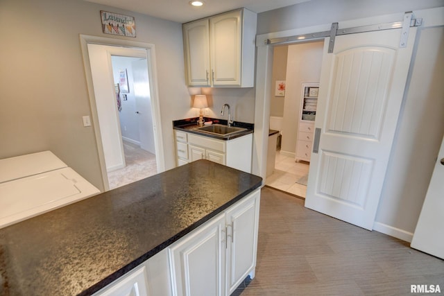 kitchen featuring a barn door, white cabinetry, and sink