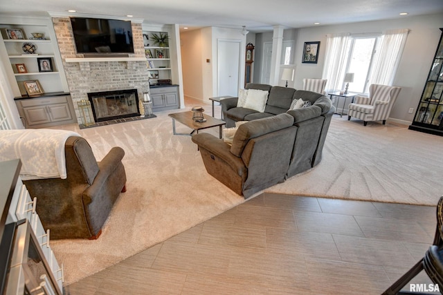 living room with built in shelves, light colored carpet, and a brick fireplace