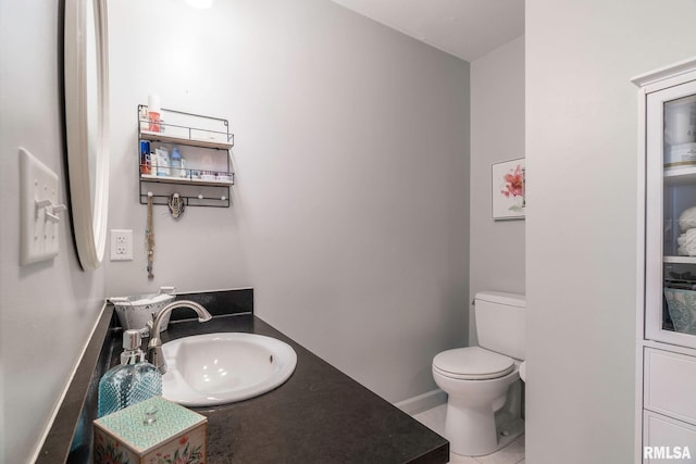 bathroom with toilet, vanity, and tile patterned floors