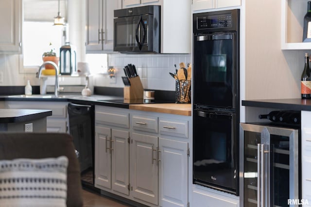 kitchen featuring beverage cooler, sink, black appliances, white cabinets, and butcher block counters