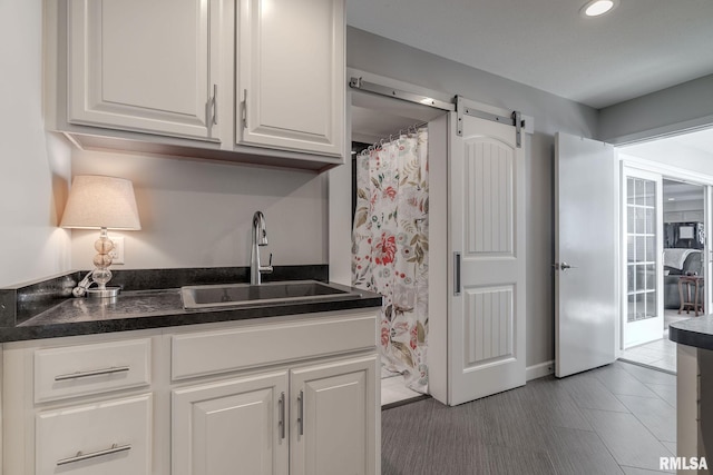 kitchen with a barn door, white cabinetry, and sink