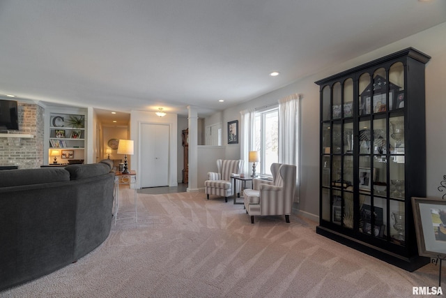 living room with carpet flooring, a fireplace, built in features, and ornate columns