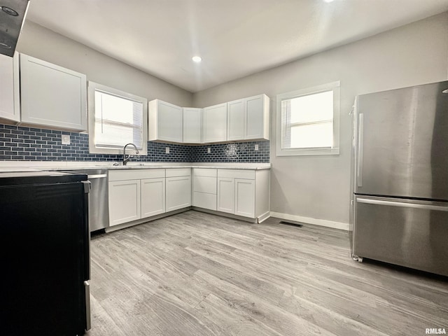 kitchen with white cabinets, stainless steel fridge, light hardwood / wood-style floors, and sink