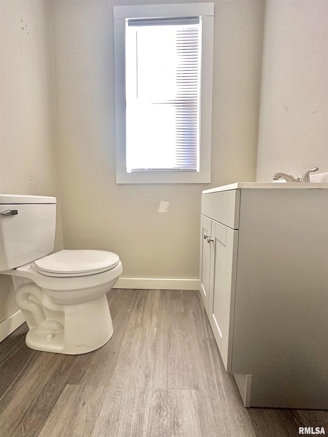 bathroom with toilet, vanity, and hardwood / wood-style flooring