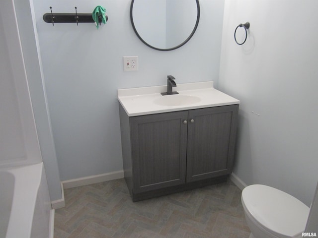 bathroom featuring parquet floors, a bathtub, vanity, and toilet