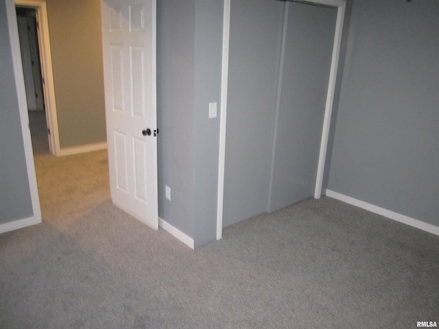 unfurnished bedroom with light colored carpet and a closet