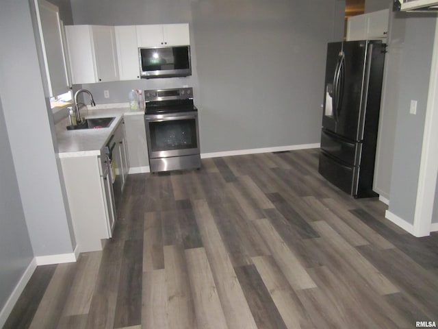 kitchen featuring white cabinets, appliances with stainless steel finishes, dark hardwood / wood-style flooring, and sink