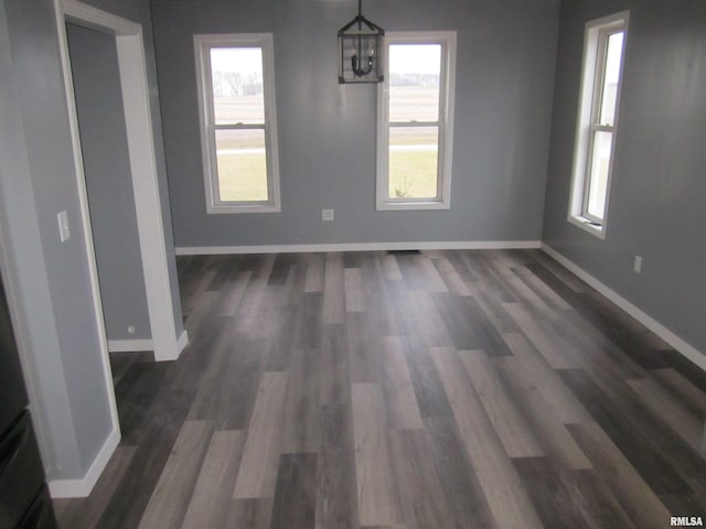 unfurnished dining area with a notable chandelier, dark hardwood / wood-style floors, and a healthy amount of sunlight