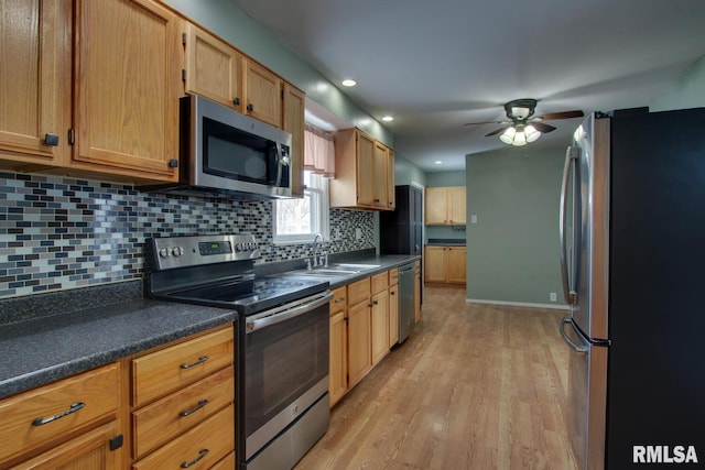 kitchen featuring sink, light hardwood / wood-style flooring, ceiling fan, decorative backsplash, and stainless steel appliances